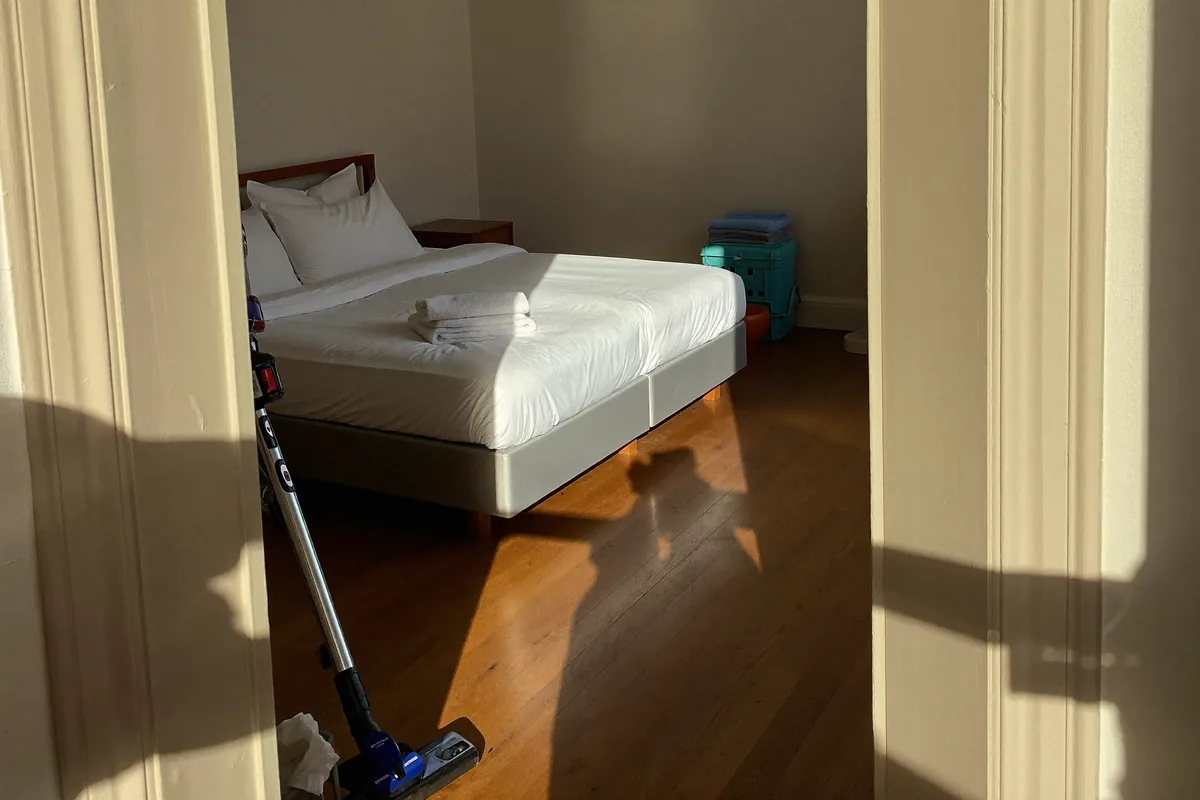 Freshly made bed with folded towels in a sunlit Lisbon studio